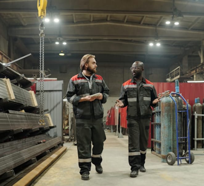 Two engineers in high-visibility coveralls walking a materials yard